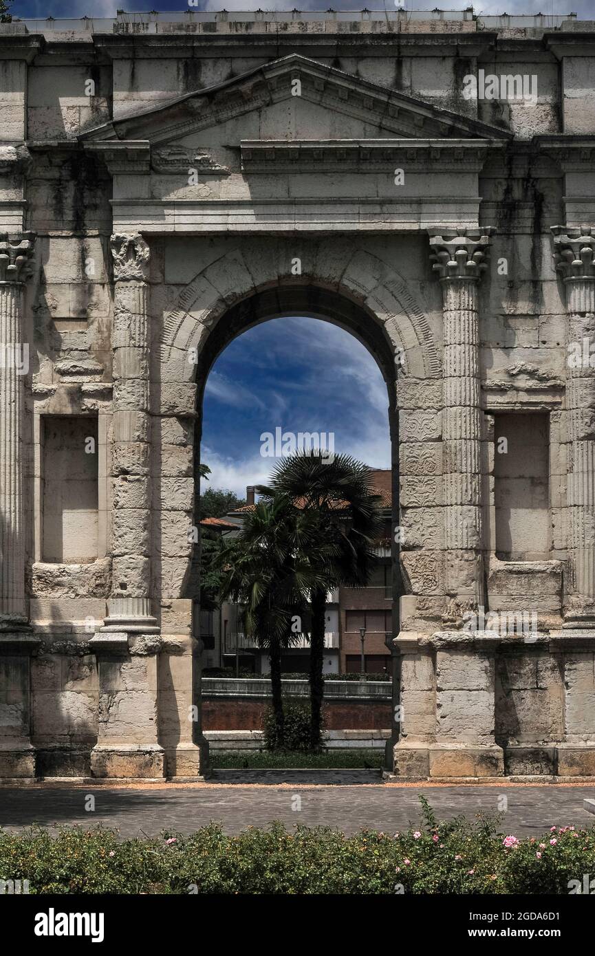 The Arco dei Gavi in Verona, Veneto, Italy: built to glorify a powerful Ancient Roman family, demolished by Napoleon Bonaparte’s military engineers, left as a heap of stones under an arch of the city’s Roman Arena, but then rebuilt in 1932 by Prime Minister Benito Mussolini as part of his campaign to encourage Italians to identify with their country’s illustrious Roman past.  A short section of black basalt Roman roadway relaid beneath the arch is grooved by the wheels of ancient carts and chariots. Stock Photo