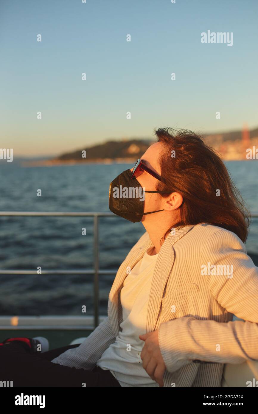 Woman with mask and sunglasses on a commuter boat. Stock Photo