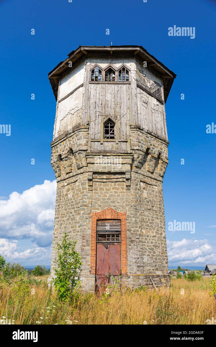 Old stone water tower with windows and a wooden roof against the ...