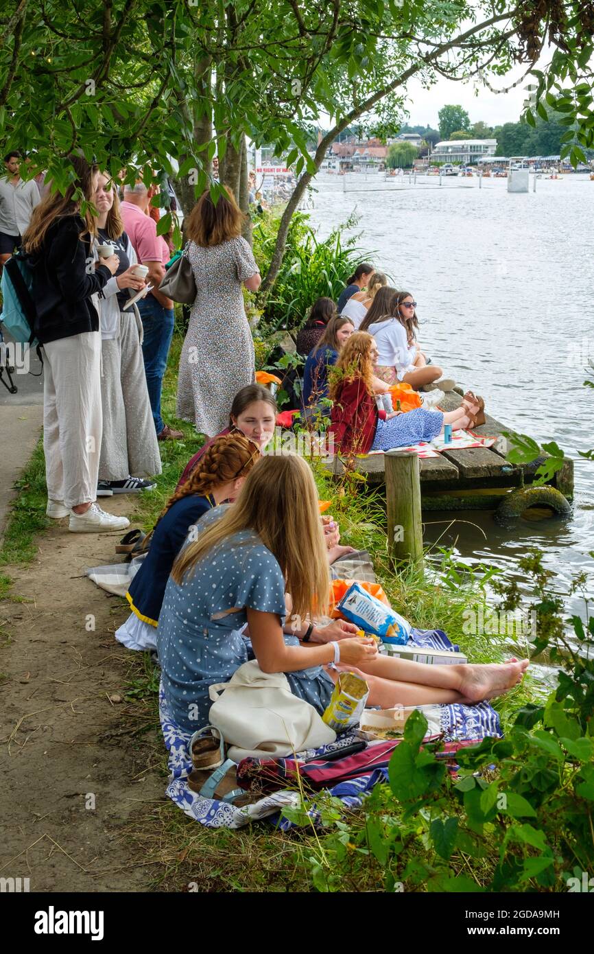 Young spectators picnic by the towpath on the banks of the Thames at Henley Royal Regatta 2021 Stock Photo