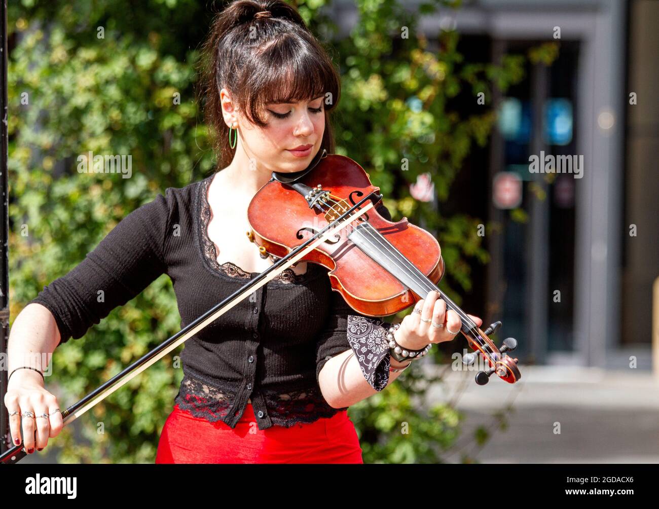 Dundee, Tayside, Scotland, UK. 12th Aug, 2021. UK Weather: A warm windy day with plenty sunshine across North East Scotland with temperatures reaching 18°C. A young fashionable female violinist playing classical music whilst busking outside The Overgate shopping centre in Dundee. Credit: Dundee Photographics/Alamy Live News Stock Photo