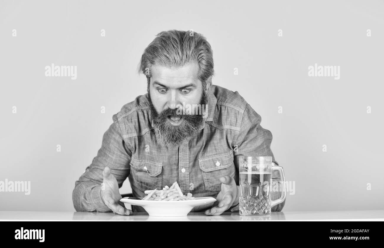 man with fast food. beer and french fries in restaurant. eating and drinking at bar. hipster relax in tavern. bearded guy having snack. lazy man Stock Photo