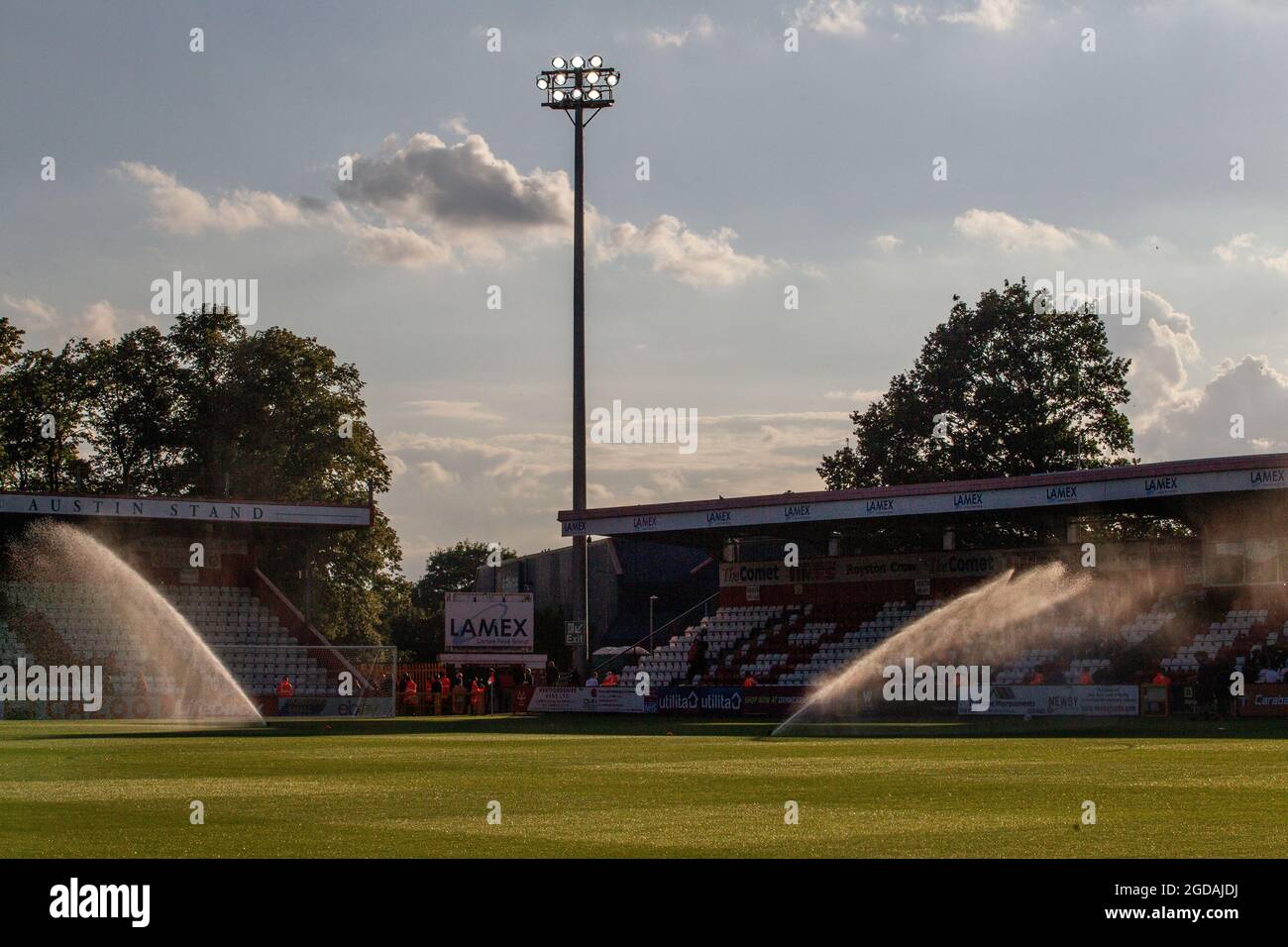 Football pitch at lower league ground at dusk with sprinklers watering the pitch. Stock Photo