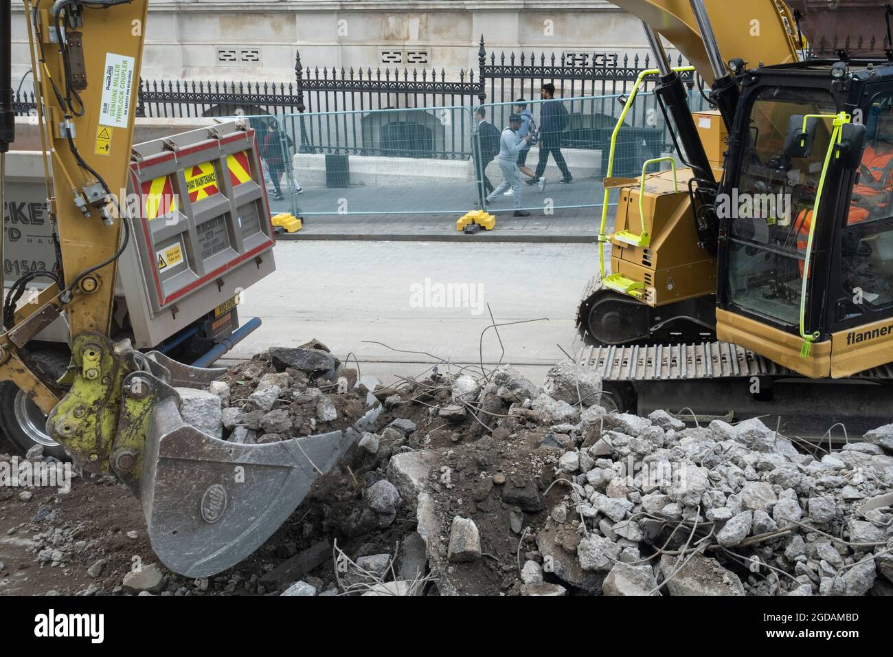 Workman operating a digger lifts large quantities of rubble into a truck at the construction site for work on the update to the Midland Metro tram public transport system in the city centre along Corporation Street on 3rd August 2021 in Birmingham, United Kingdom. The original tracks are being pulled up and relaid, while a new line is also under construction and due to open later in the year. The Midland Metro is a light-rail tram line in the county of West Midlands, England, operating between the cities of Birmingham and Wolverhampton via the towns of West Bromwich and Wednesbury. The line op Stock Photo