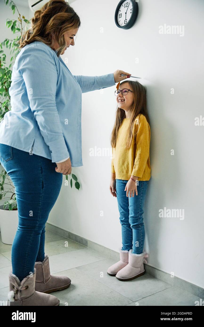 daughter mother measuring height growth childhood Stock Photo