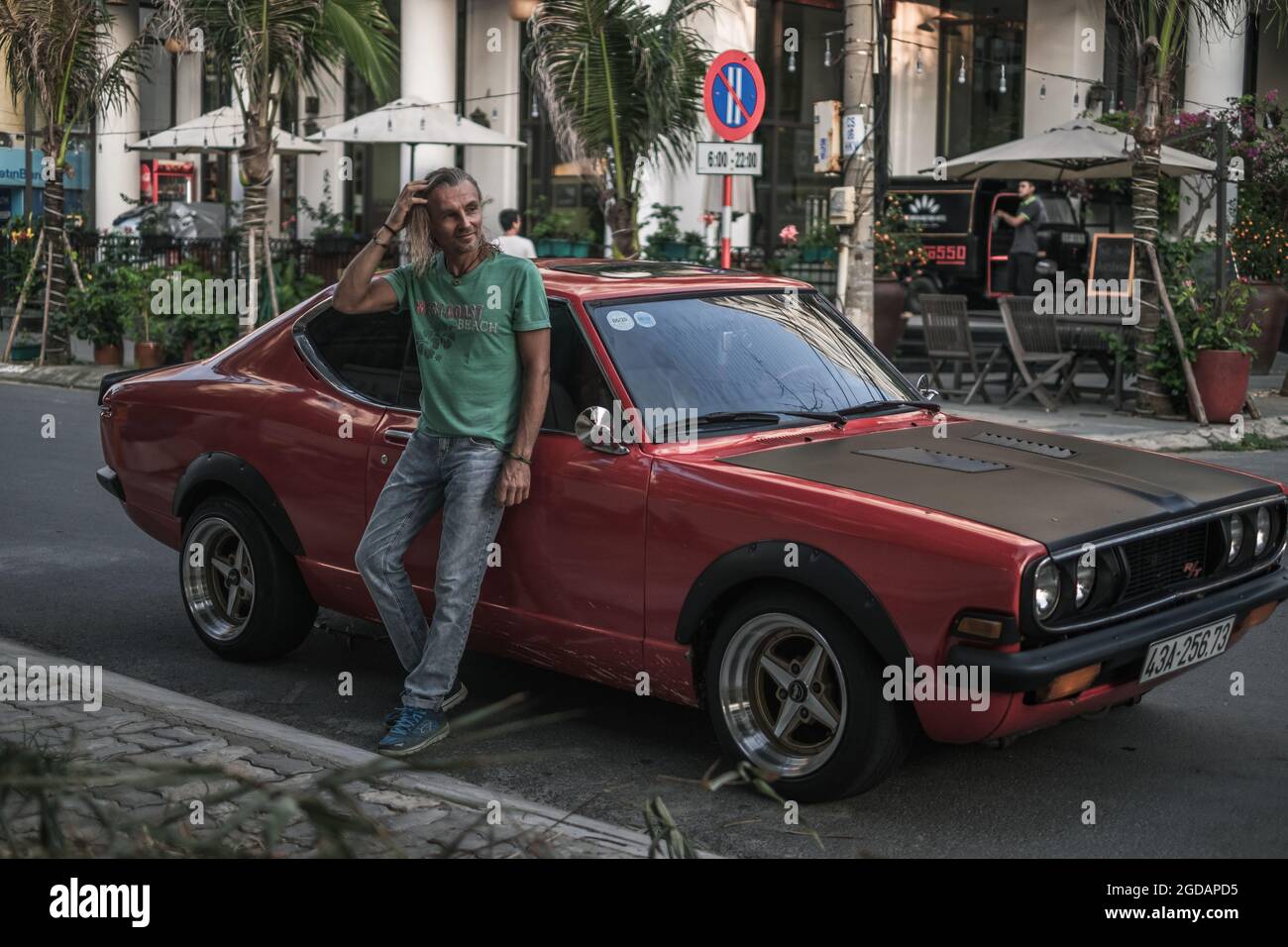 Mature handsome man in t-shirt, jeans and cap standing near the red retro  car on the street in town and holding his hair. Long grey hair. High  quality Stock Photo - Alamy