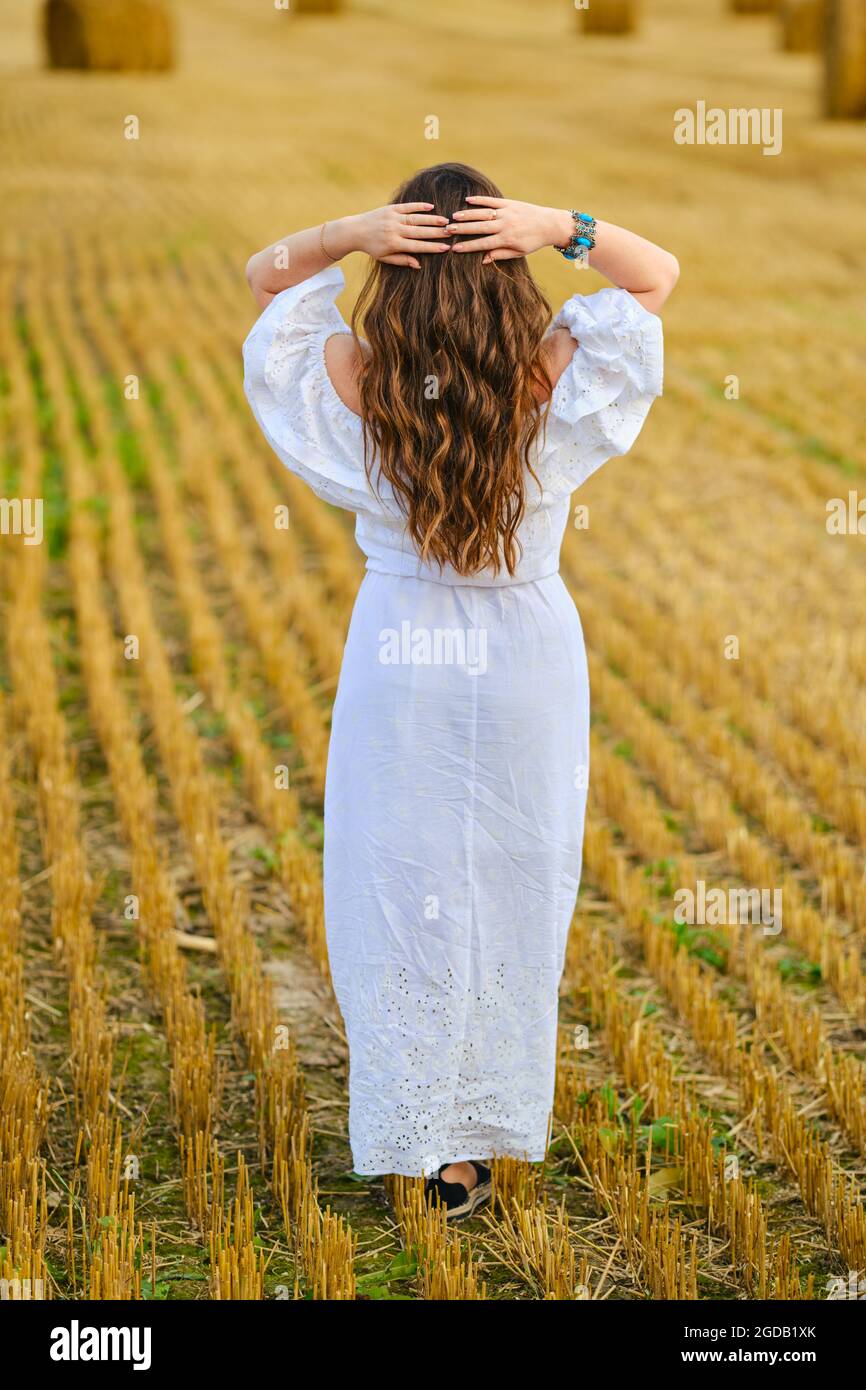 Rear view of pretty young woman holding hands behind her head while ...