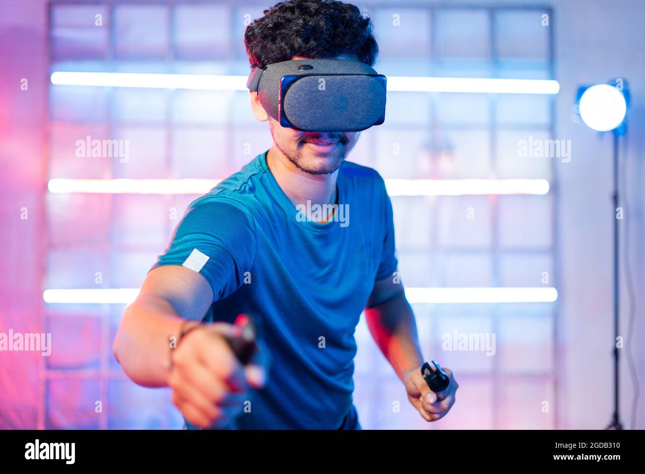 Young man playing video game by wearing vr or virtual reality goggles and holding joysticks in hands - concept of modern gaming technology Stock Photo
