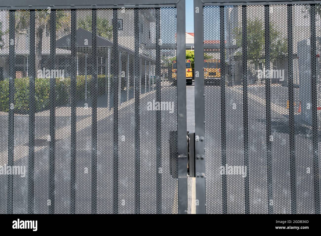 School buses waiting to pick up students seen behind locked gates. Stock Photo