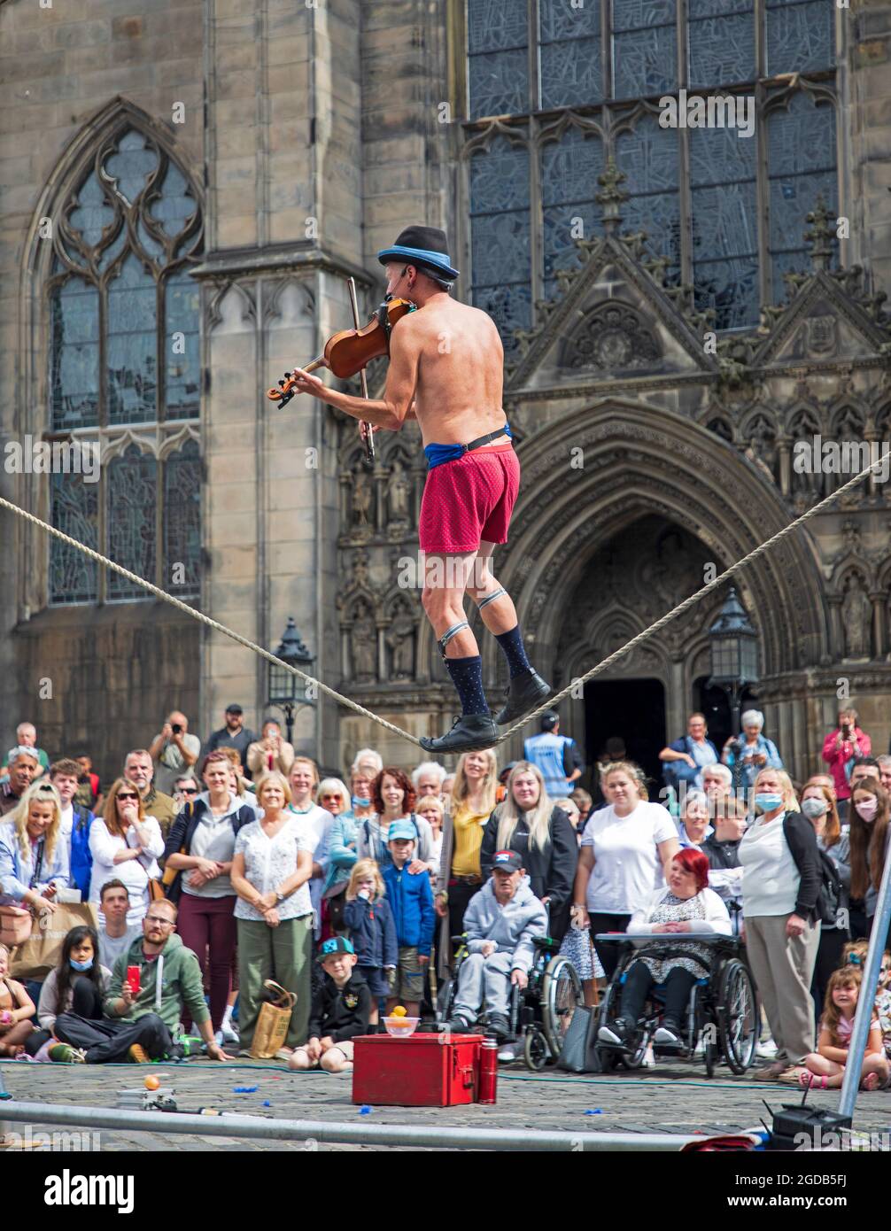 Royal Mile, Edinburgh, Scotland, UK. 12th Aug, 2021. Edinburgh Fringe Festival, day seven of the goings on on the capital city High Street event. Weather breezy and cloudy with temperature of 18 degrees for the human statues and street performers drawing crowds to their pitches. Pictured: Kwabana Lindsay entertains a large audience on Parliamnet Square. Credit: Arch White/Alamy Live News Stock Photo