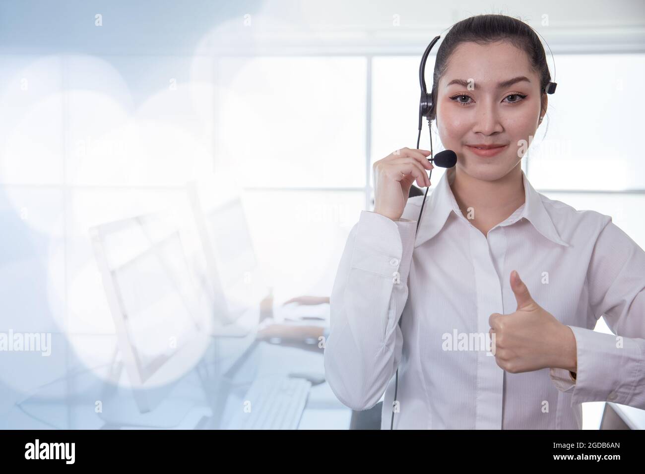 Portrait Asian callcenter operator thumbs up. Helpdesk support phone call customer care female staff smiling with headset good service concept with sp Stock Photo