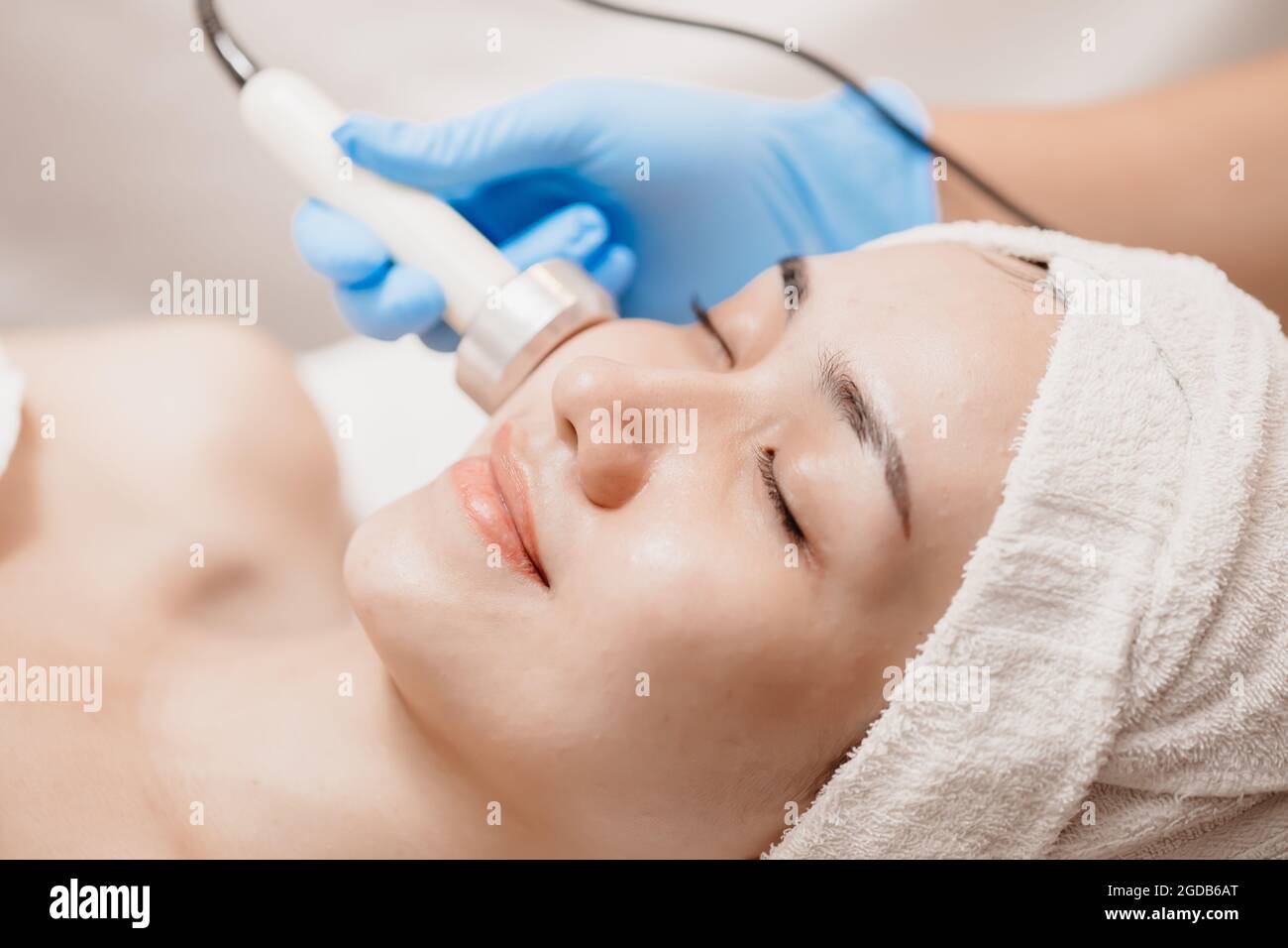 Ultrasonic facial skin massage with women happy face skincare tightening in beauty salon spa. Stock Photo