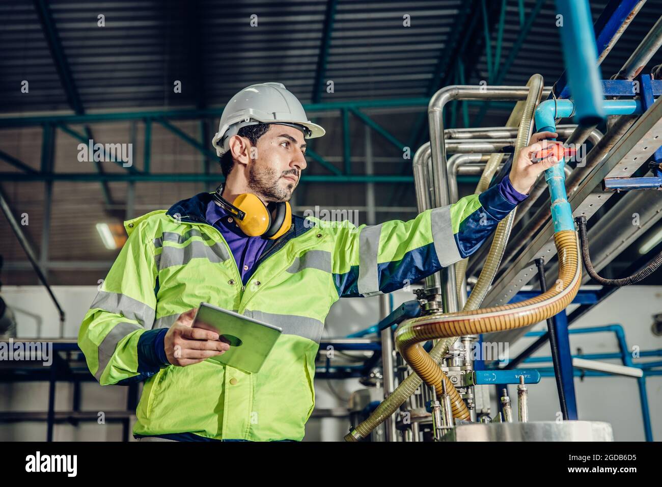Young hispanic latin engineer working in a heavy industrial factory. worker control oil gas water pipe in plant. Stock Photo
