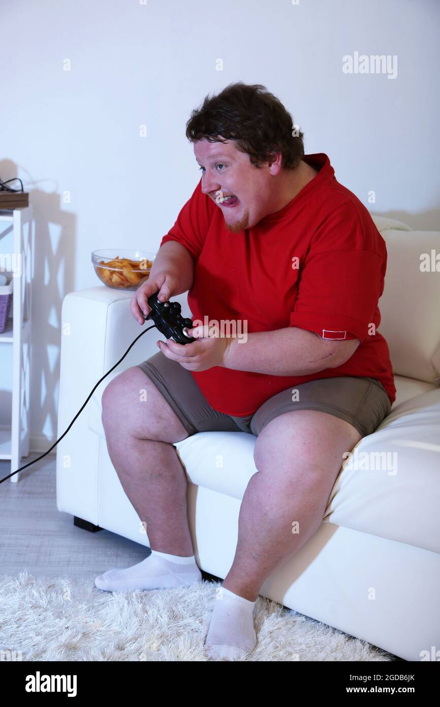 Fat man playing video games on home interior background Stock Photo - Alamy