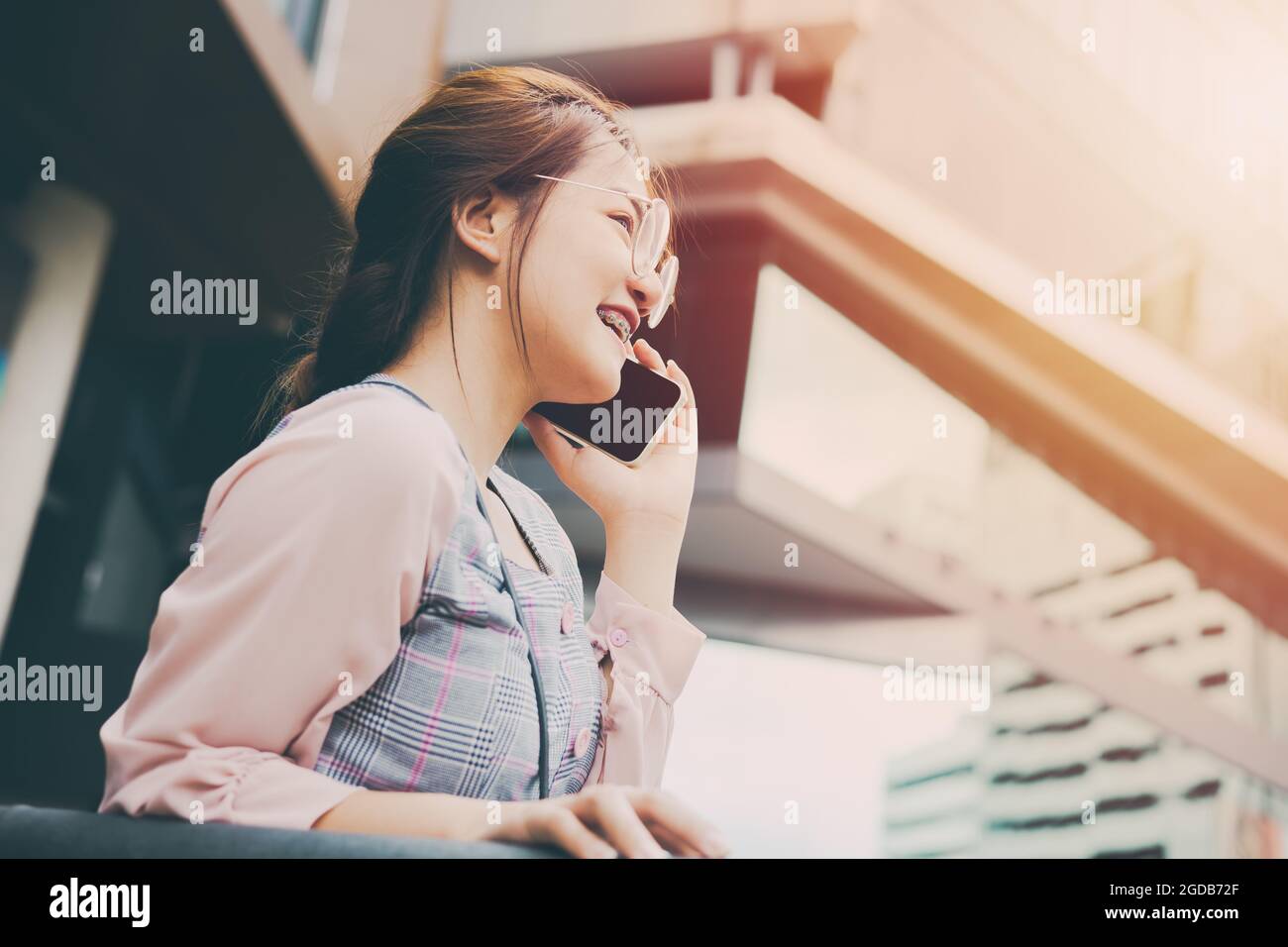 Teen girl using smartphone calling communication with happy smiling in modern city background vintage tone. Stock Photo