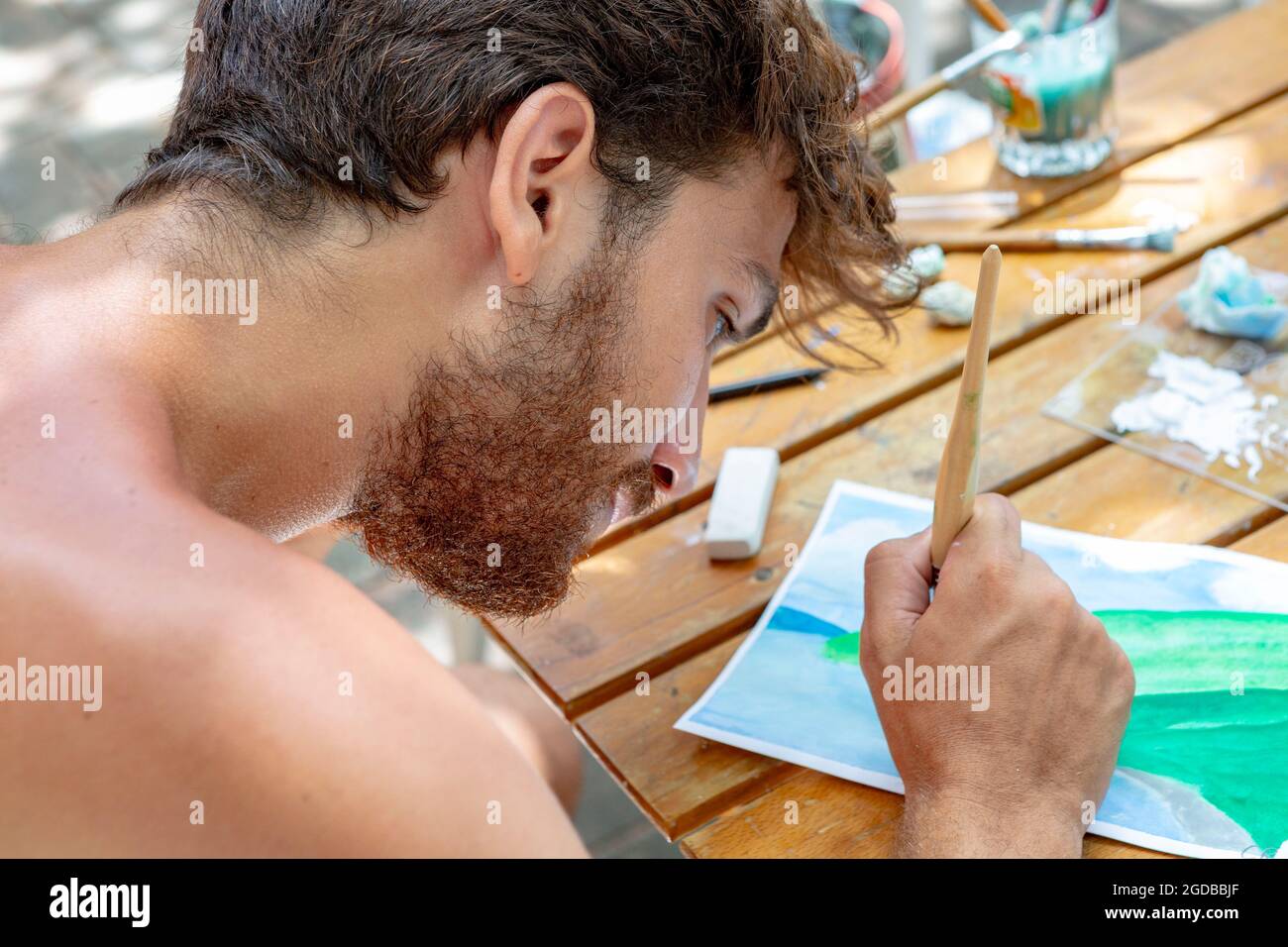 Young man painting water colours seen from over shoulder Stock Photo