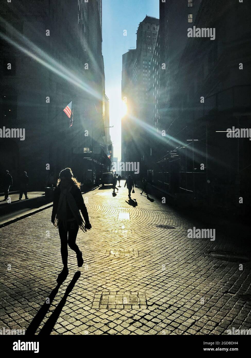 Silouette of people on a cobblestone street in lower Manahattan near the New York Stock Exchange. Stock Photo