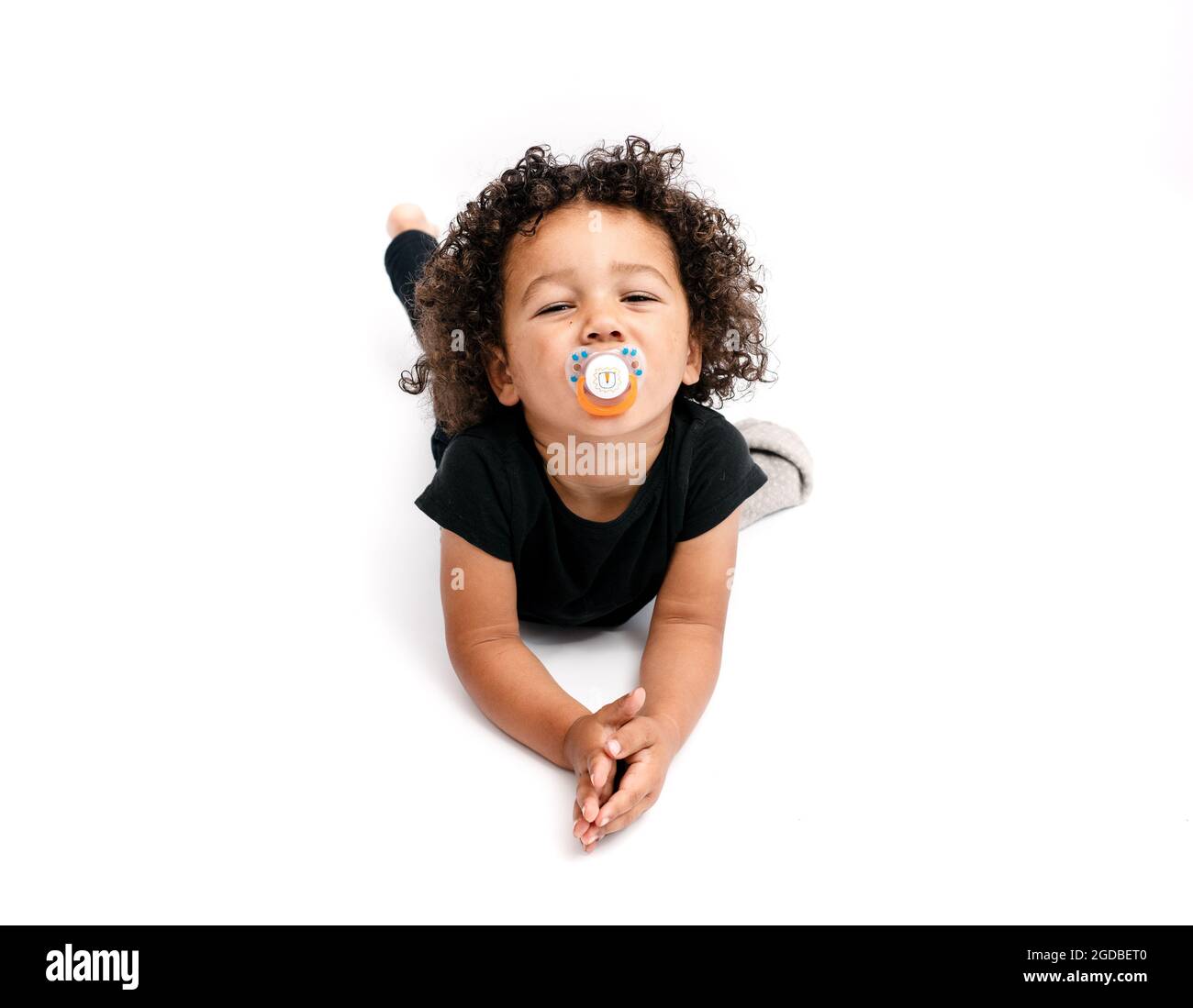 Horizontal portrait of a smiling mixed race 2 years and half old boy sucking a nipple Stock Photo