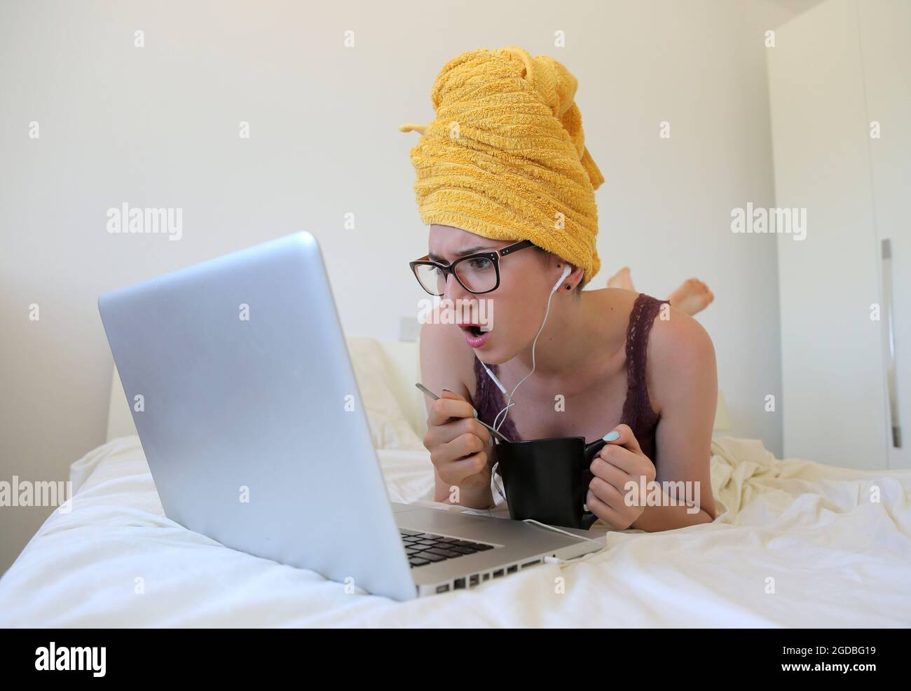 Young Caucasian female with a towel wrapped around her head looking at ...