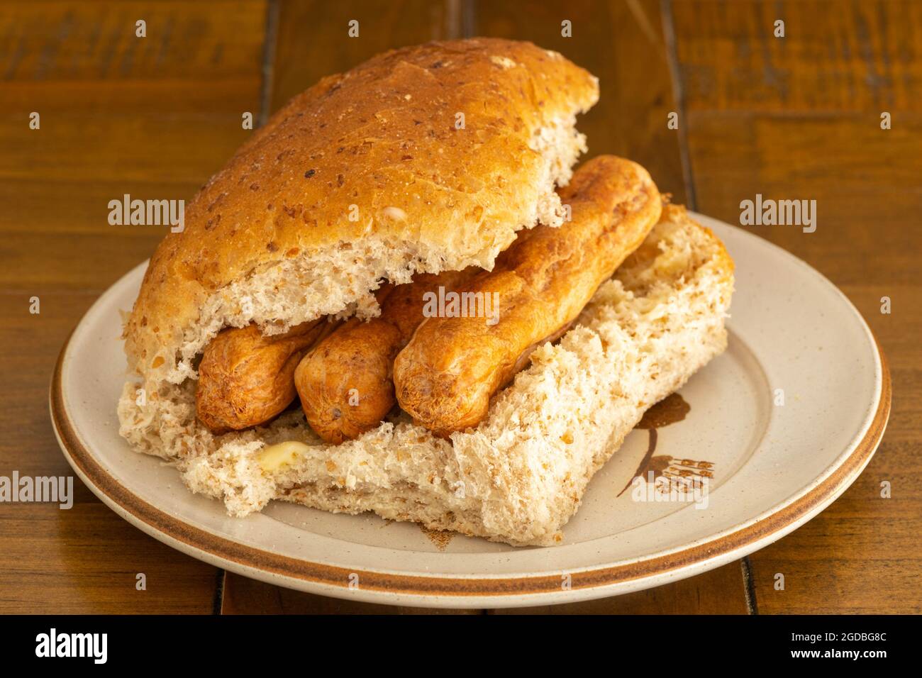 A wheaten and oatmeal roll filled with three scottish pork link sausages Stock Photo