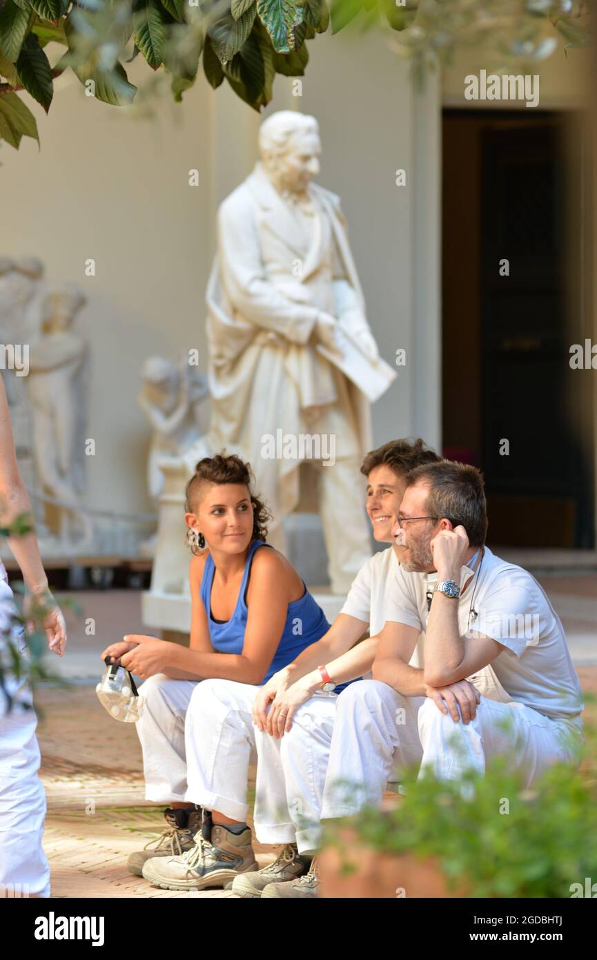 Sculptors wearing overalls sitting in outdoors in a sculpture workshop in Rome taking a break Stock Photo