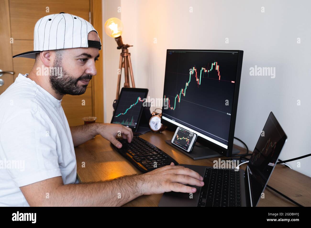 young man examines financial statements and graphs with 3 monitors from his  home. The young man is happy with the cryptocurrency market Stock Photo -  Alamy