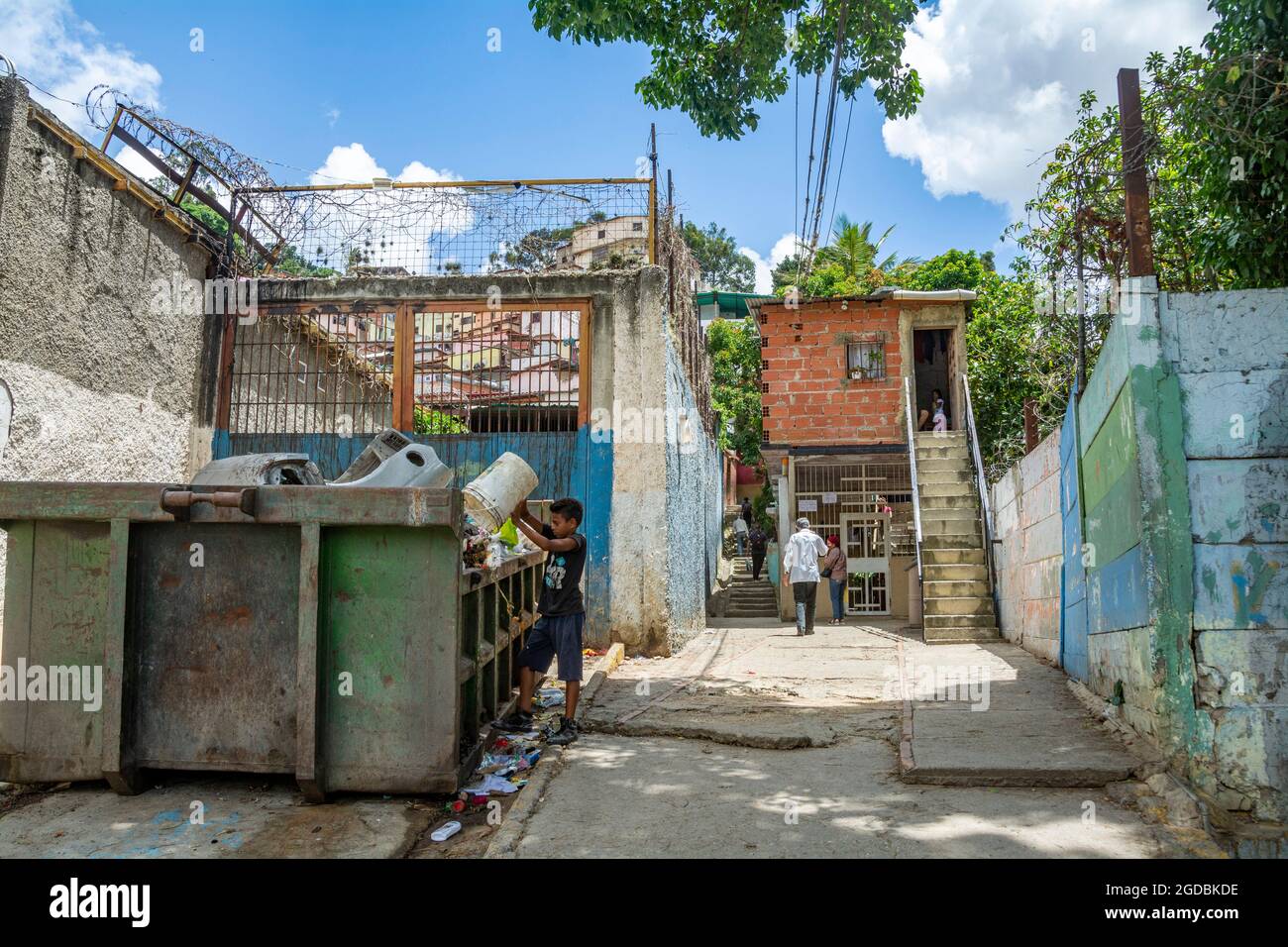 A boy throws garbage into a garbage bin at the entrance of the Las Mayas neighborhood in Caracas, Venezuela. The problem of garbage collection and dis Stock Photo