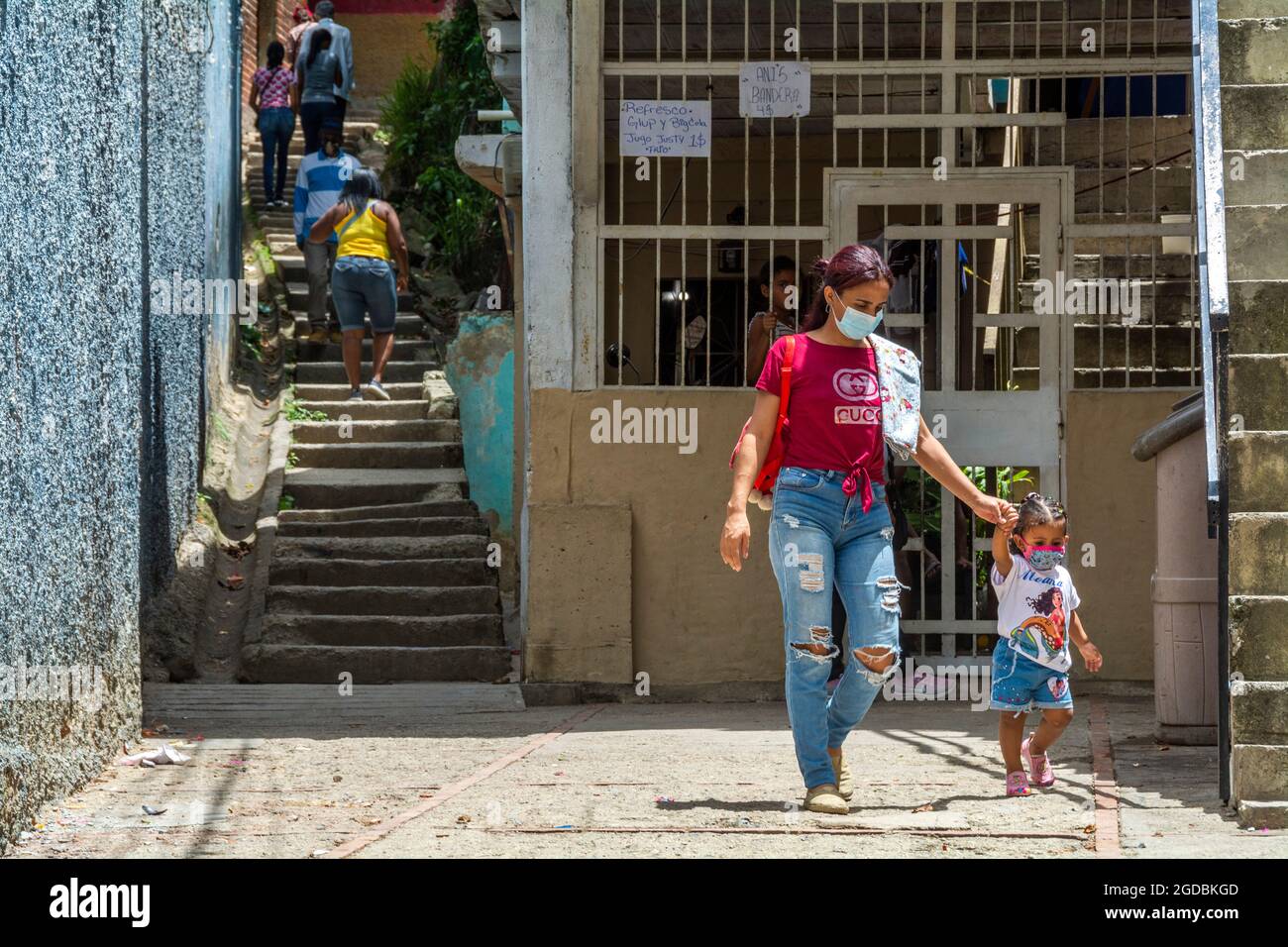 A mother and daughter leave the Las Mayas neighborhood in Caracas, Venezuela. Advertisements with the sale of soft drinks, juice and licor, are indica Stock Photo