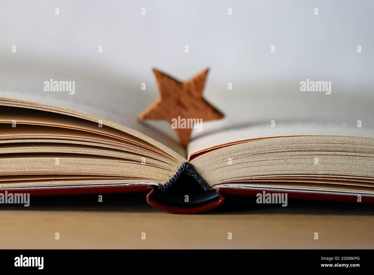 Nahaufnahme eines aufgeschlagenen Buches mit rotem Einband und einem Holzstern als Lesezeichen Stock Photo