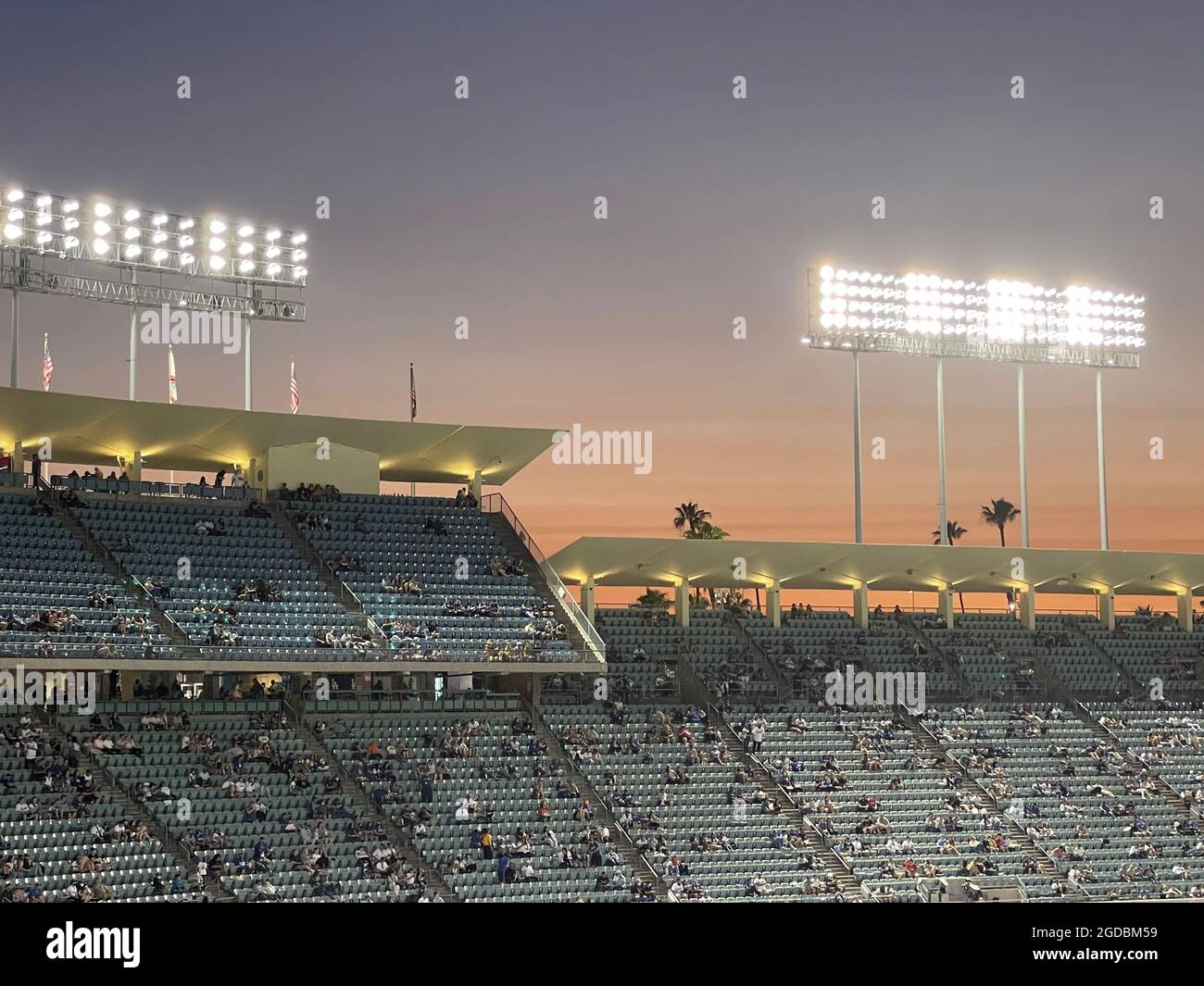 Tiers of grandstands at Dodger Stadium at dusk as lights come on in Los