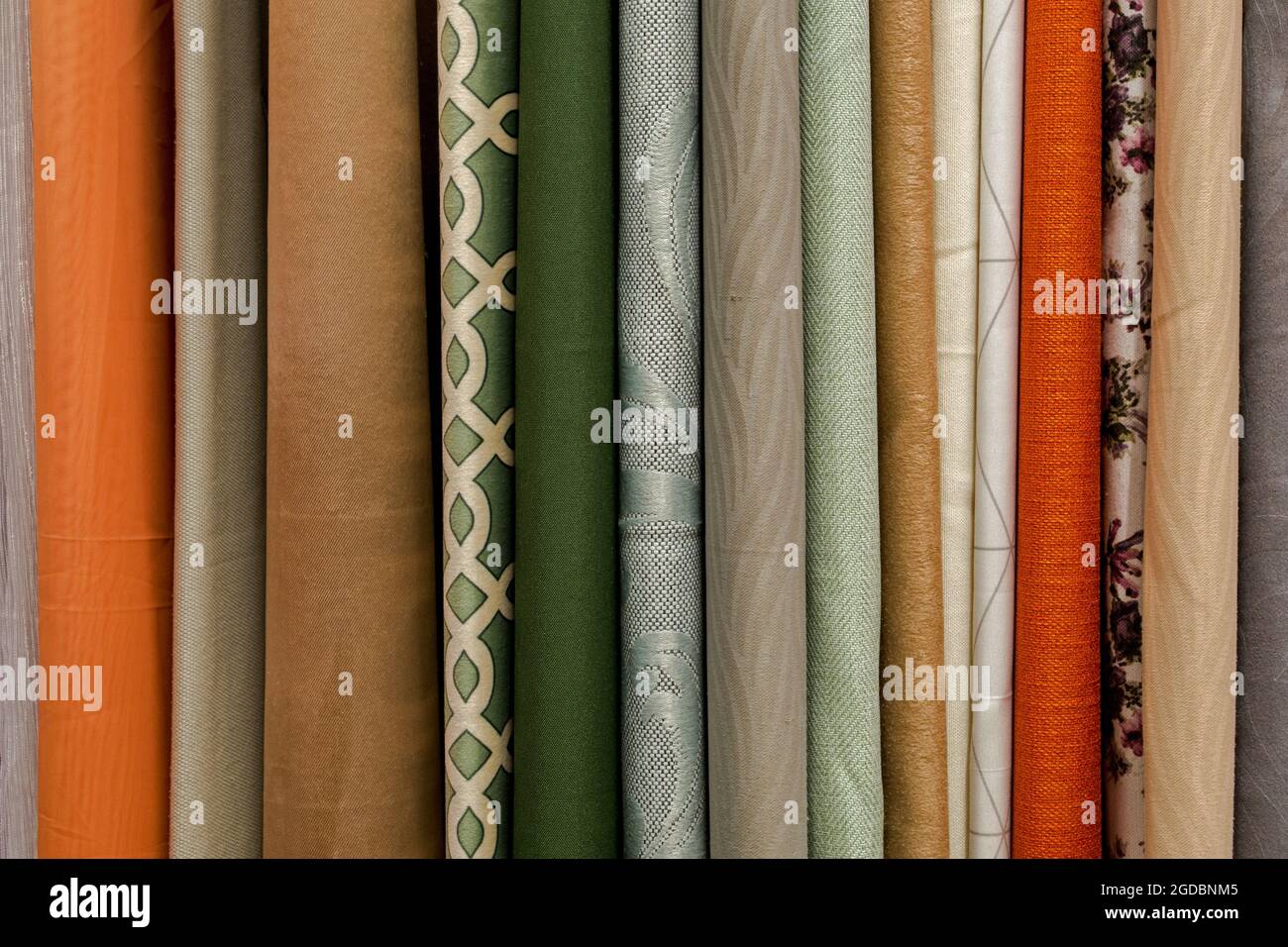 A fragment of rounded ends at the edges hangs vertically in a row of fabric curtains in green, gray, beige, orange and brown shades. Natural textile b Stock Photo