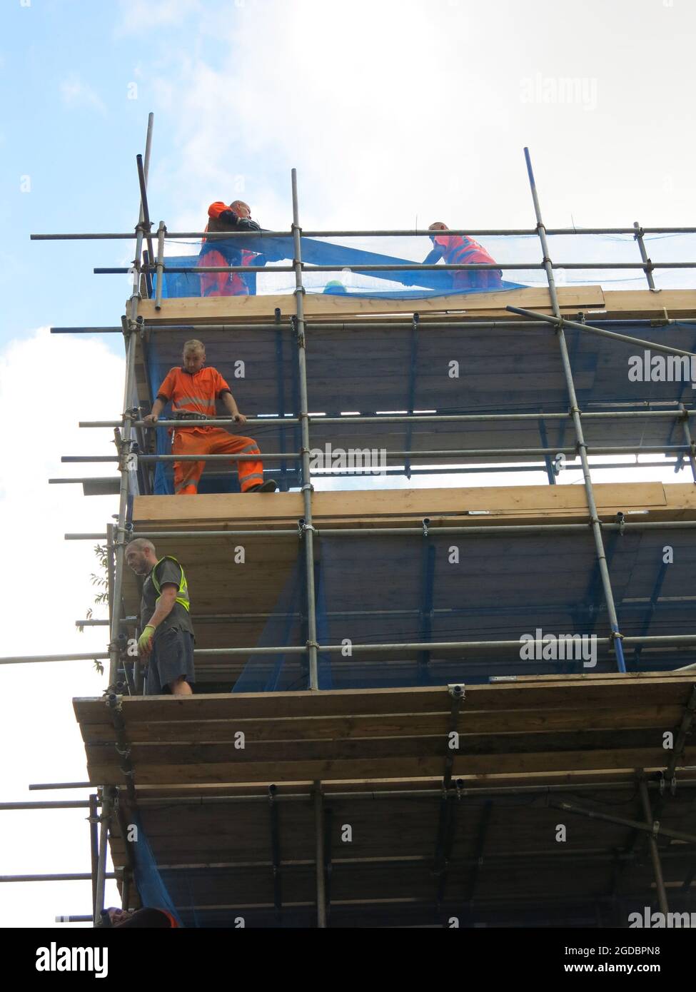 Construction workers at work on three levels of scaffolding on a