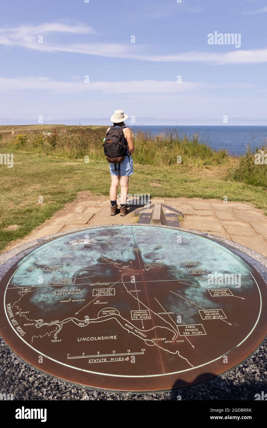 Yorkshire tourism - a female tourist stands next to a map in summer, Flamborough Head, Flamborough, East Yorkshire coast, Yorkshire UK Stock Photo