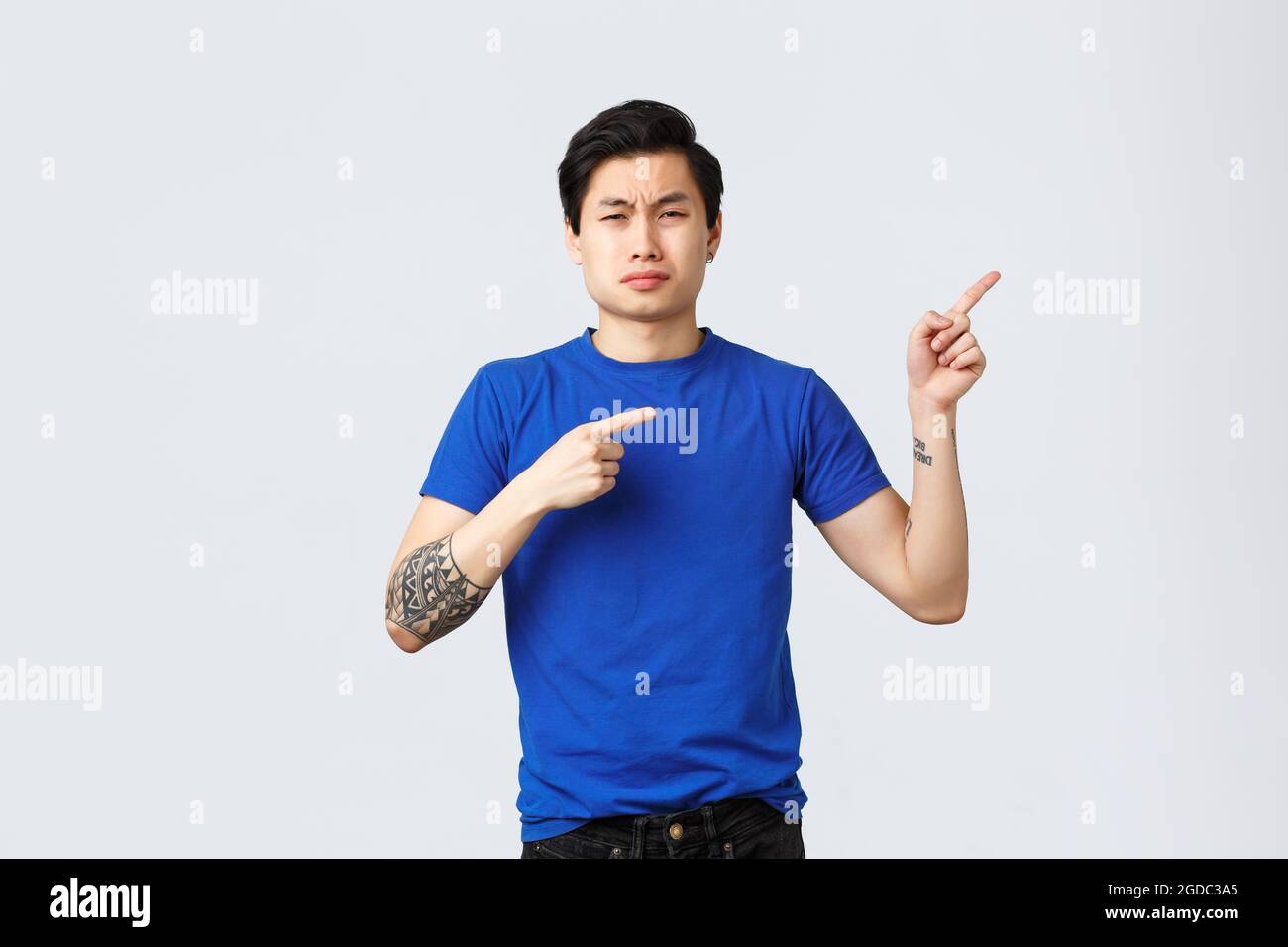 Different emotions, people lifestyle and advertising concept. Displeased and sad asian man in blue t-shirt, pointing fingers right, sobbing and Stock Photo