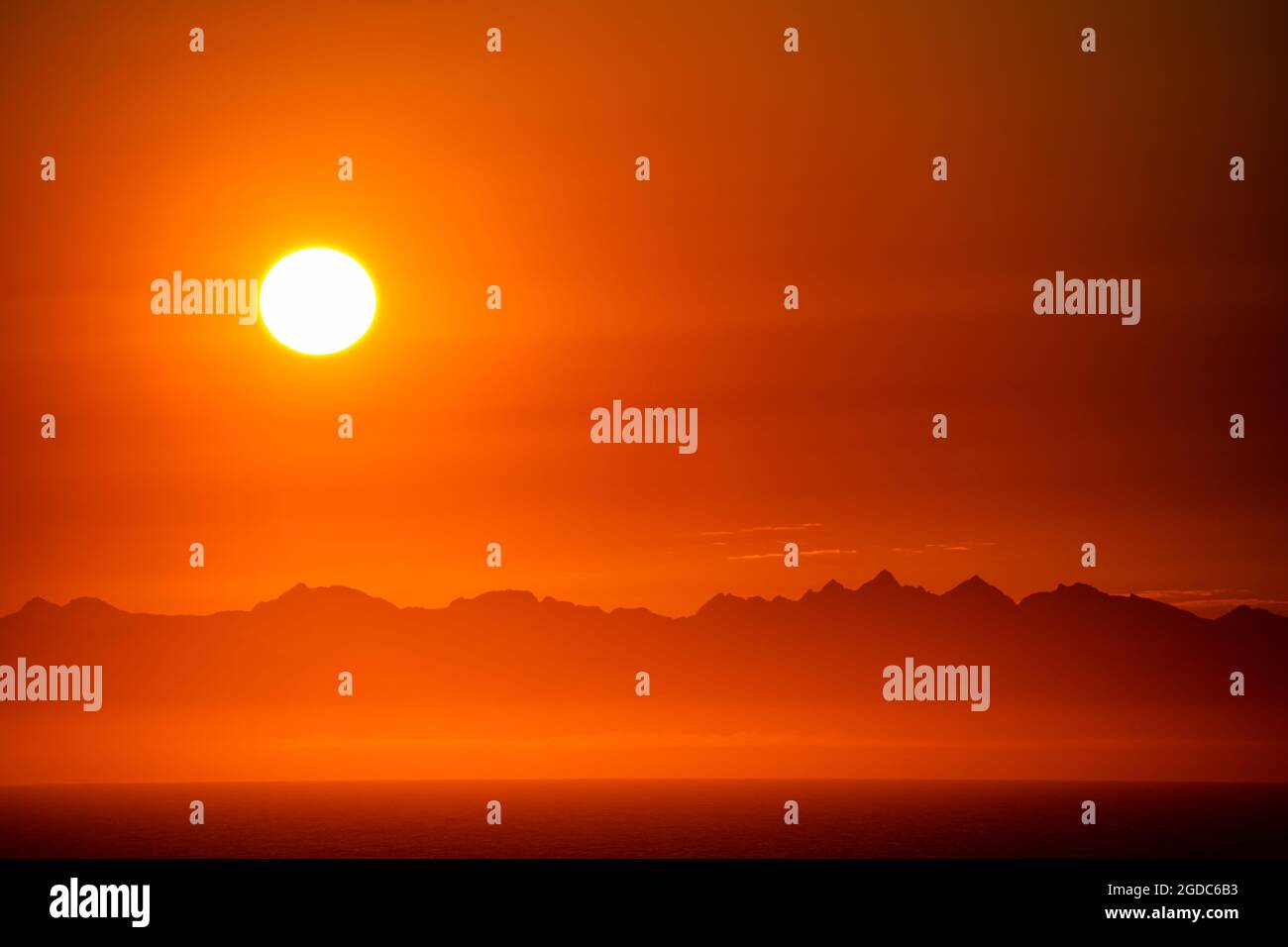 Beautiful orange sky sunrise over mountains at sea Stock Photo - Alamy
