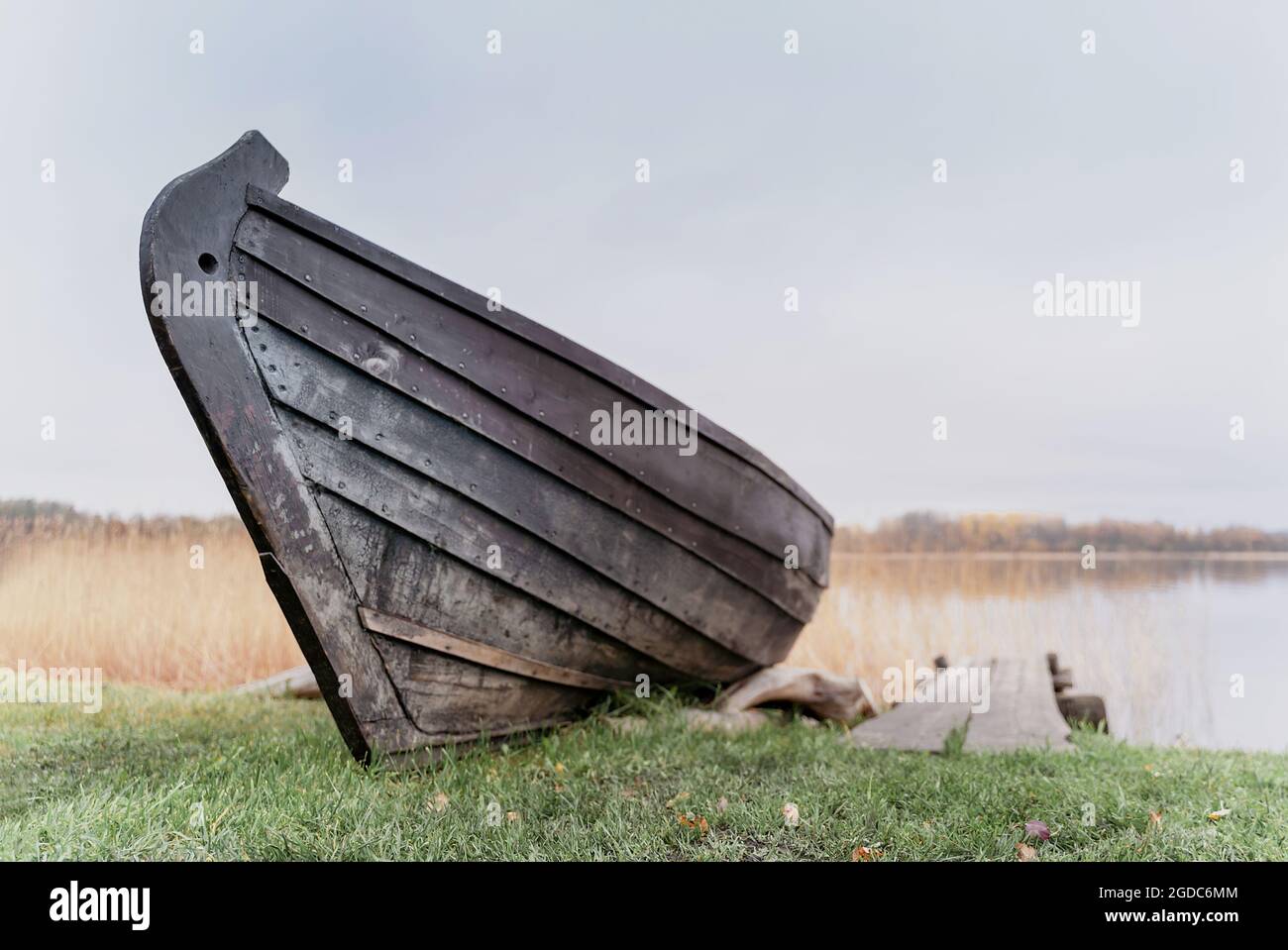 Old wooden boat on the shore of beautiful misty lake and autumn forest ...
