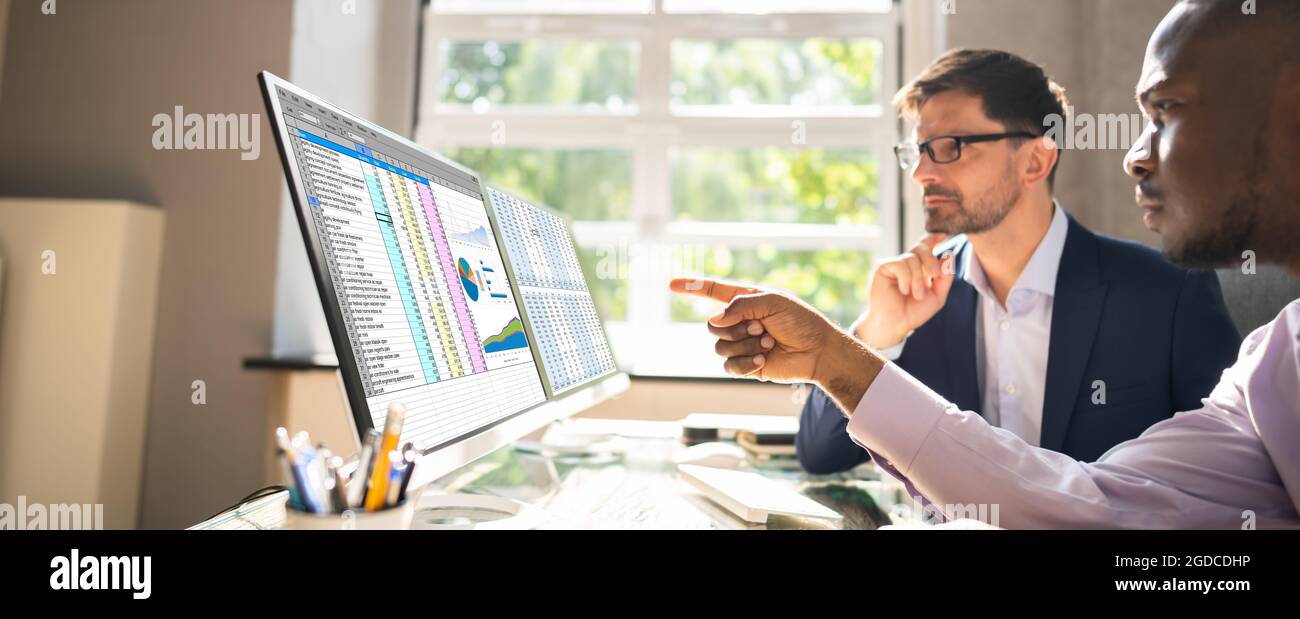 People Working With Spreadsheet Data On Computer Monitor Stock Photo