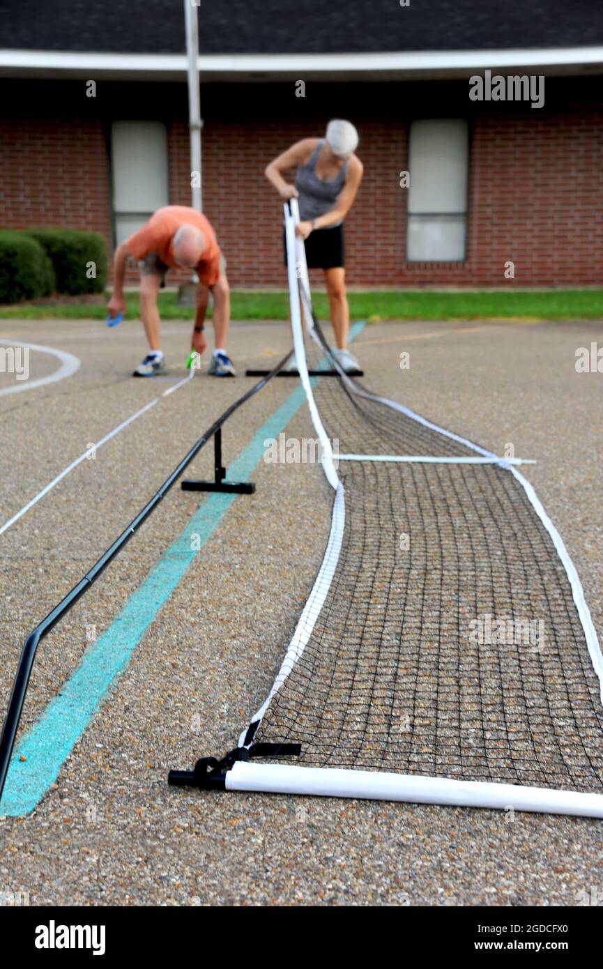 Couple constructs the net and marks the boundaries for a home pickle ball court. Stock Photo