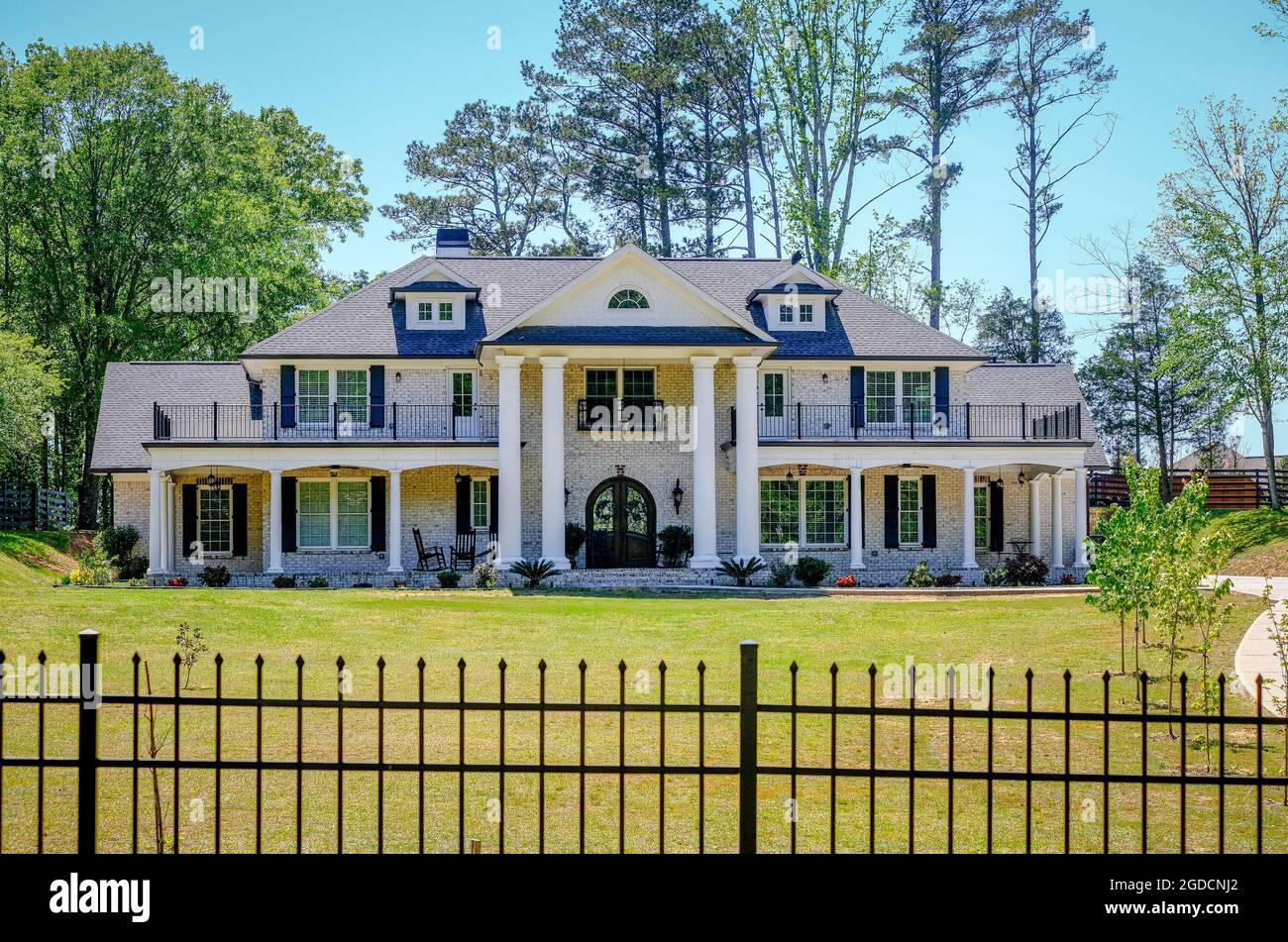 White Brick Mansion Behind Wrought Iron Fence Stock Photo