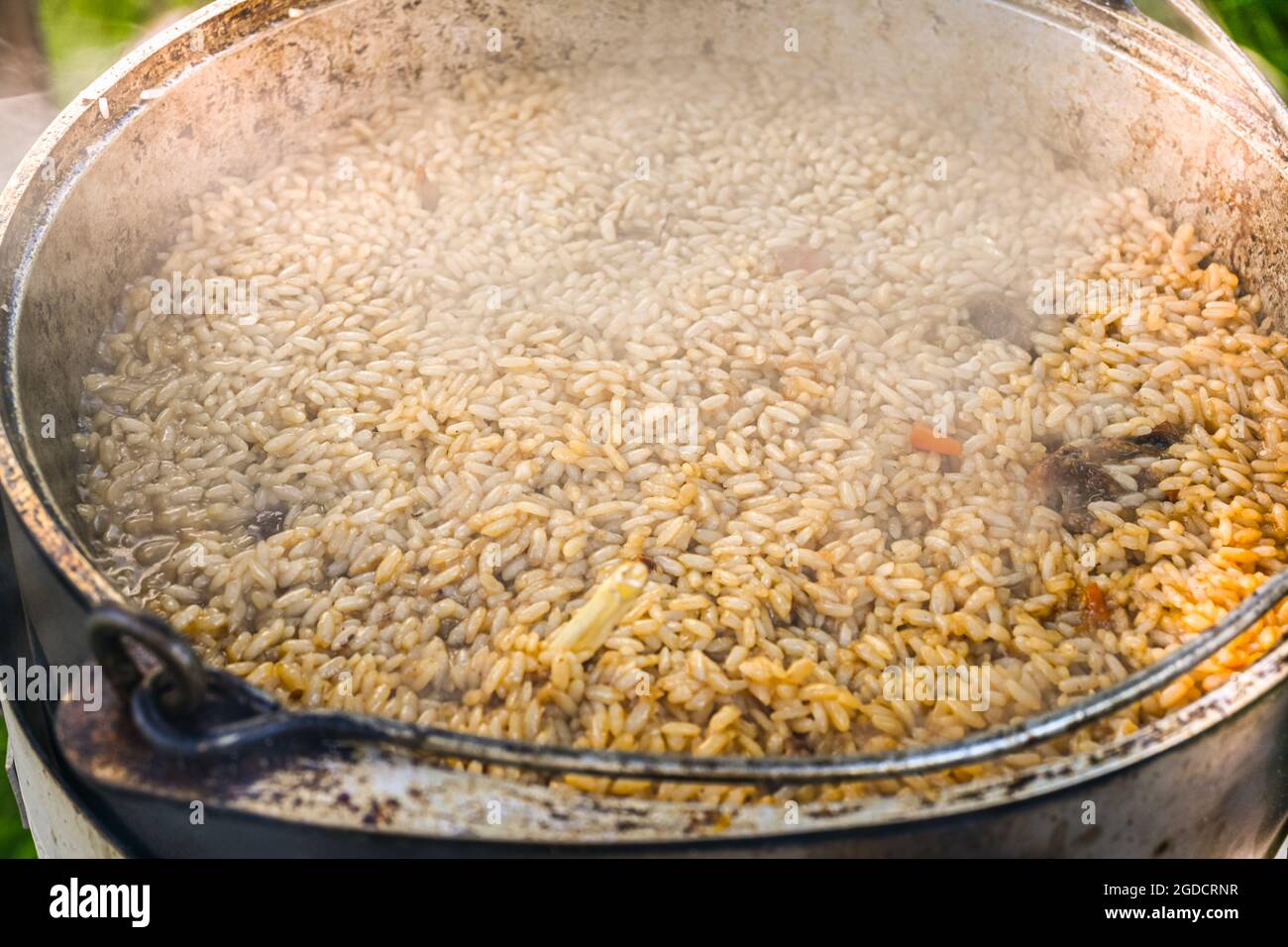 Rice in a cauldron in the process of cooking pilaf on a traditional Asian oven. Stepbystep