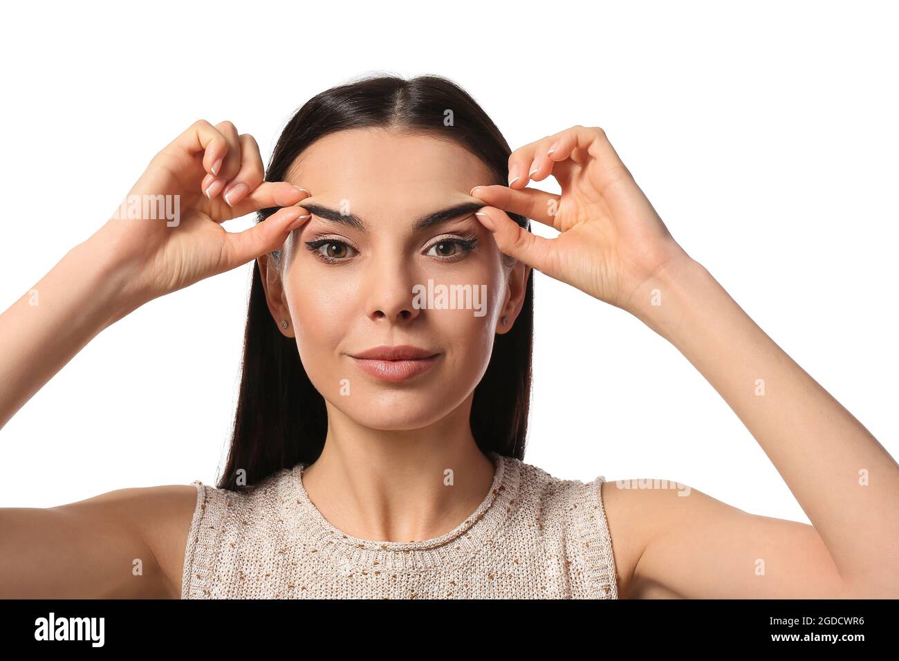 Young woman doing face building exercise against white background Stock