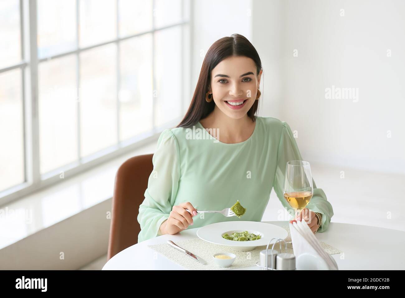 Beautiful young woman eating tasty ravioli in cafe Stock Photo - Alamy