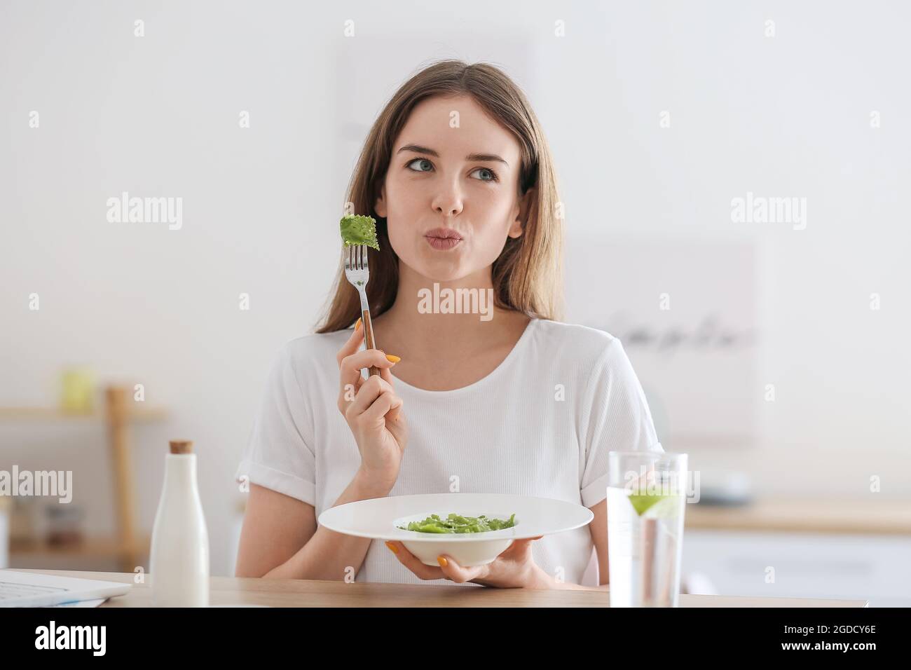 Beautiful young woman eating tasty ravioli at home Stock Photo - Alamy