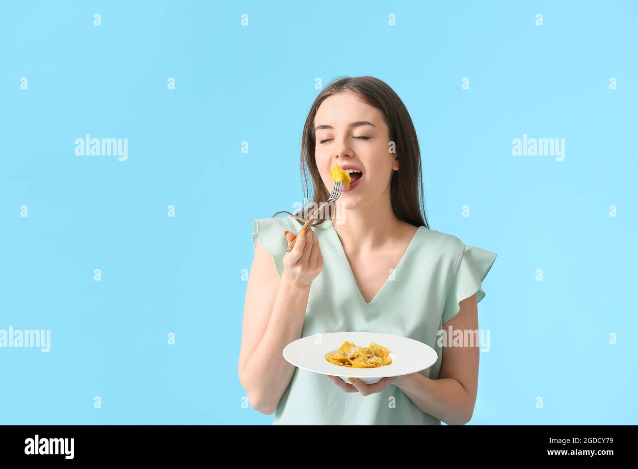 Beautiful young woman eating tasty ravioli on color background Stock ...