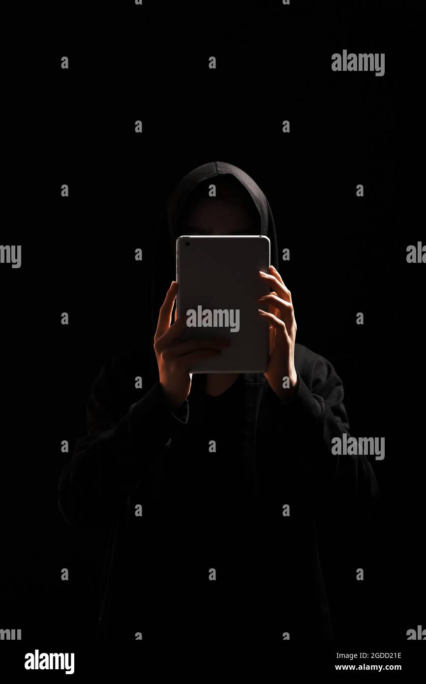 Hacker with tablet computer on dark background Stock Photo