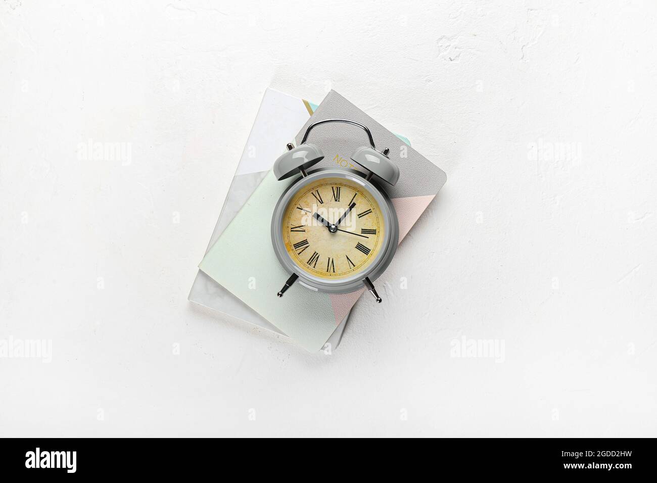 Stylish alarm clock with notebooks on white background Stock Photo Alamy