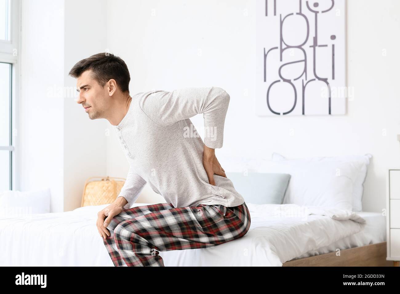 Young man suffering from back pain in bedroom Stock Photo - Alamy