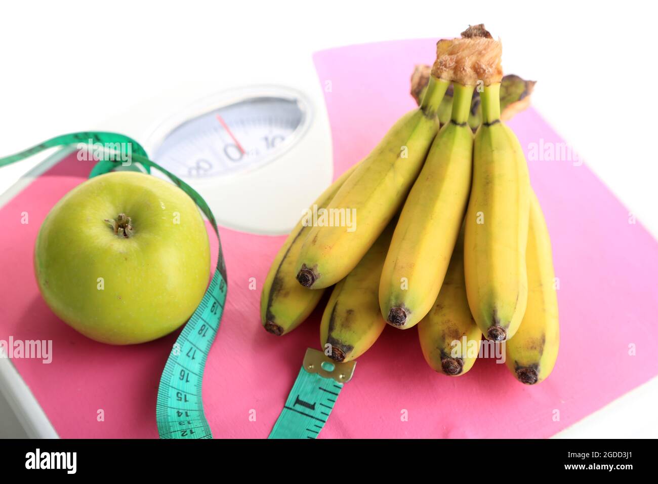 Bunch of mini bananas and measuring tape on scales, isolated on white ...
