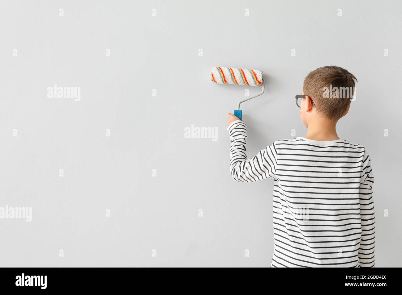 Cute little boy painting wall in room Stock Photo Alamy