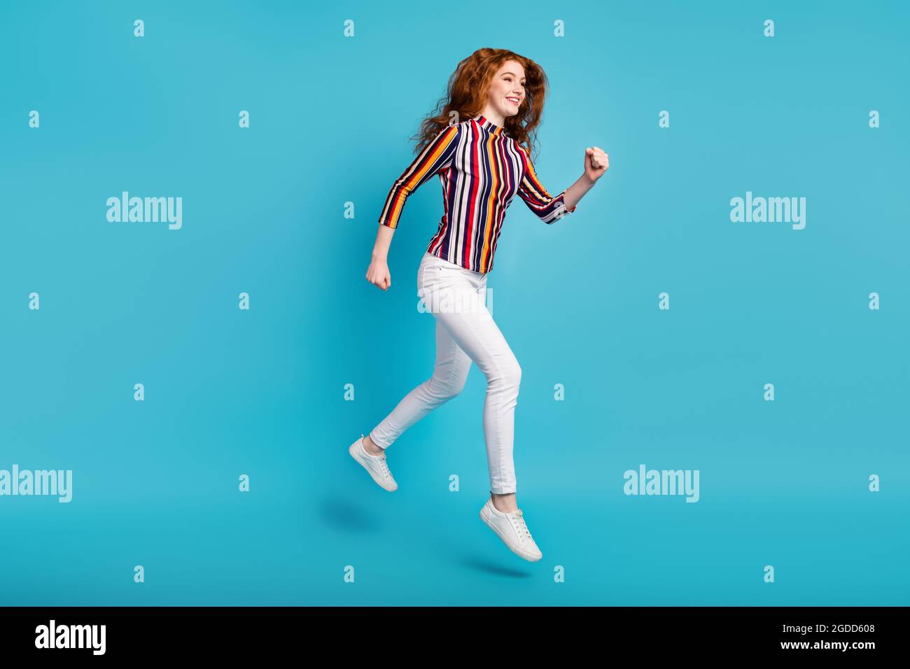 Full length body size view of attractive cheerful girl jumping running fast isolated over blue color background Stock Photo